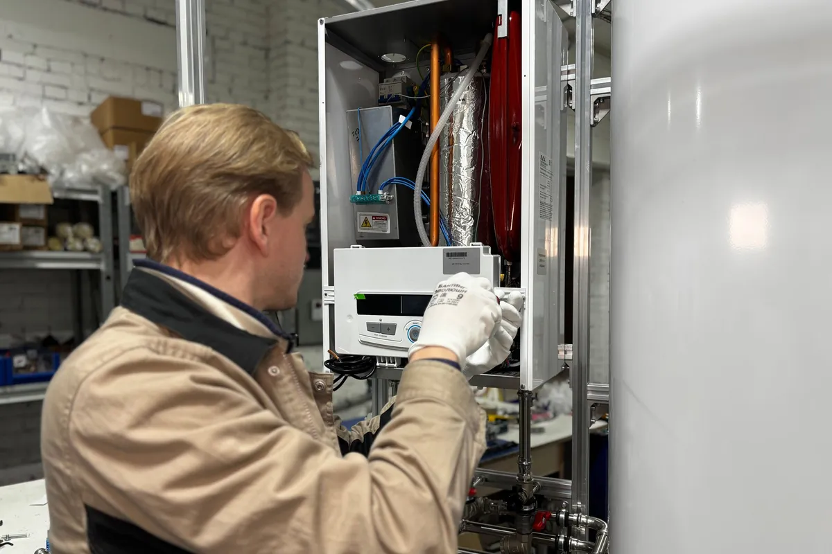 Engineer checking the pressure gauge on a wall-mounted boiler