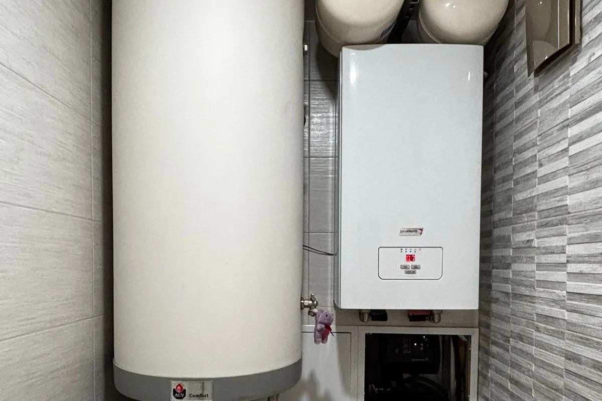New wall-mounted boiler beside a hot water cylinder
