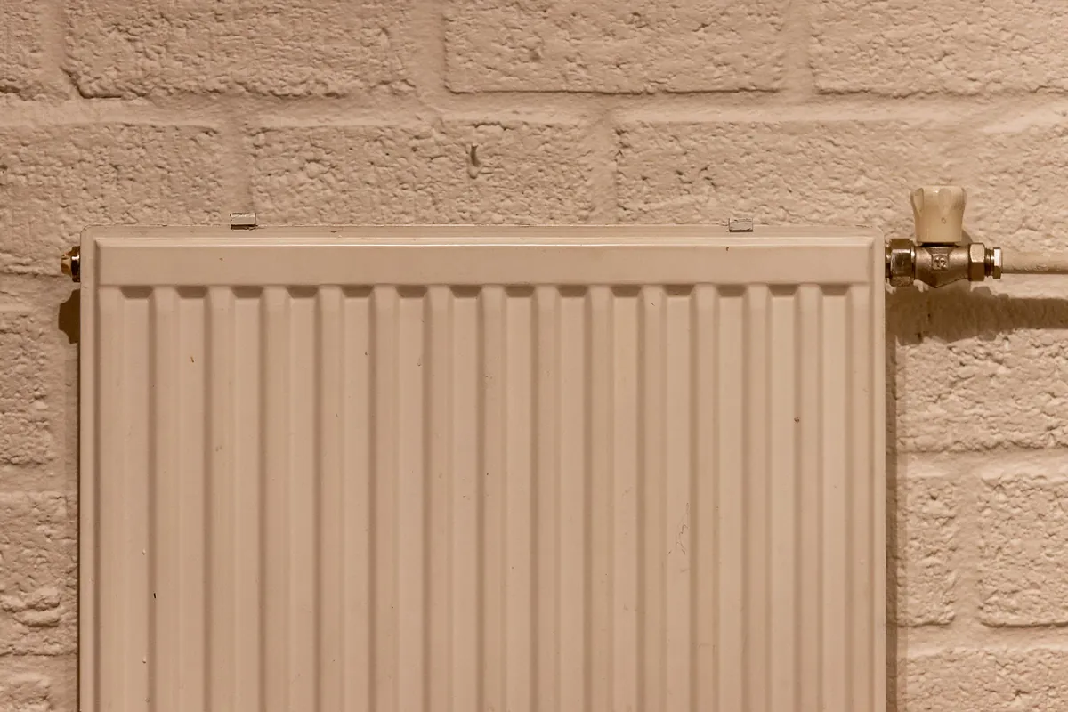 Panel radiator fitted to a painted brick wall