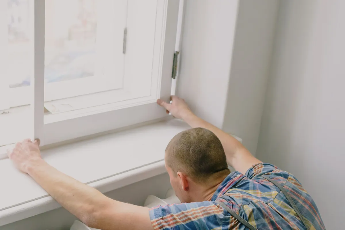Fitter positioning a radiator beneath a window