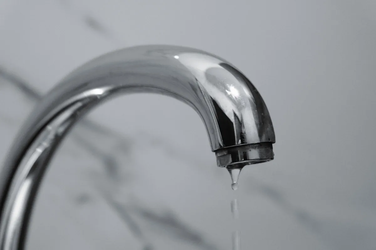 Chrome tap dripping onto a marble surface