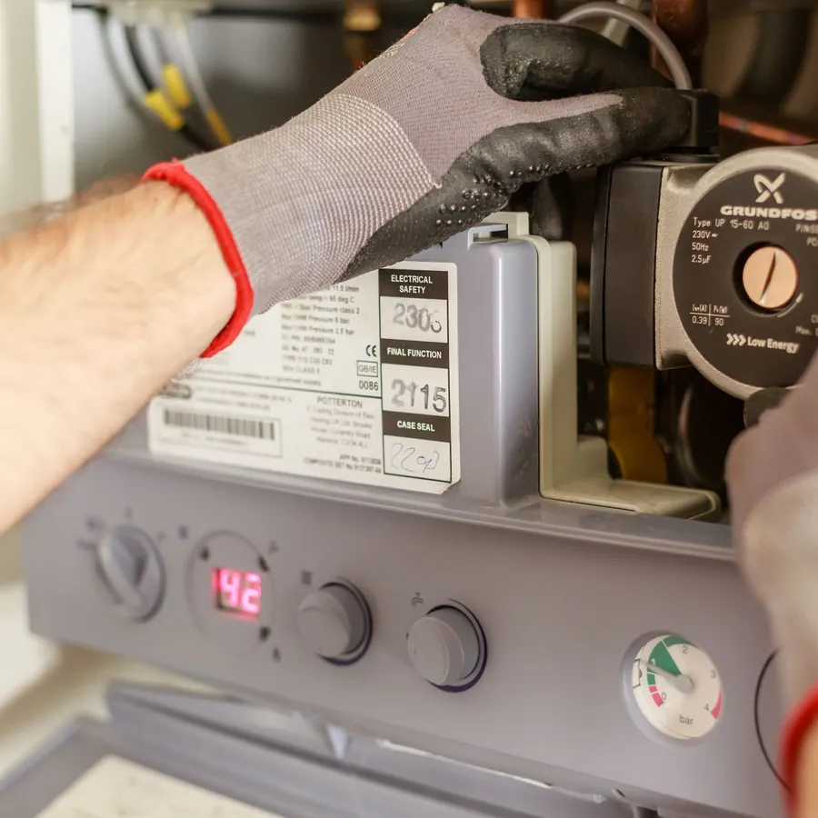 Gloved hands adjusting a boiler pump