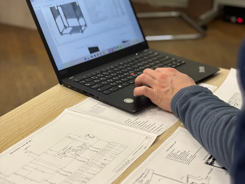 Engineer reading a job through on a laptop with drawings
